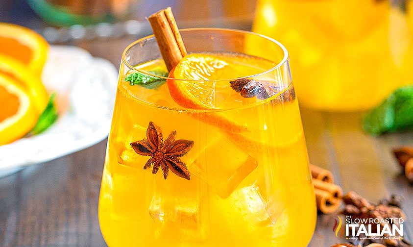 close up: glass of orange sangria with fresh fruit and spices