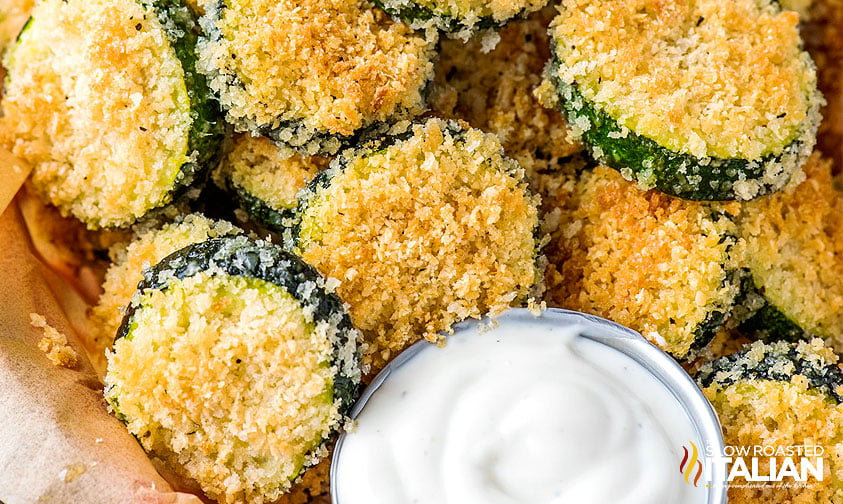 close up: baked zucchini rounds coated in panko with white dip