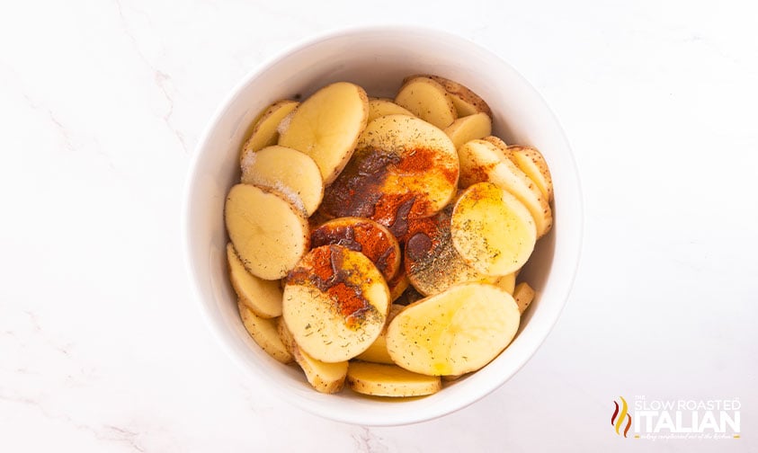 adding spices to sliced potatoes
