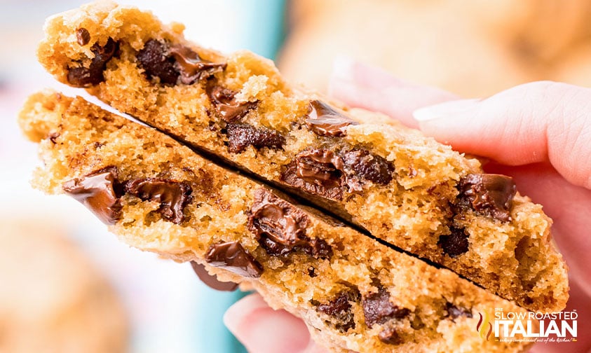 hand holding chocolate chip cookie broken in half