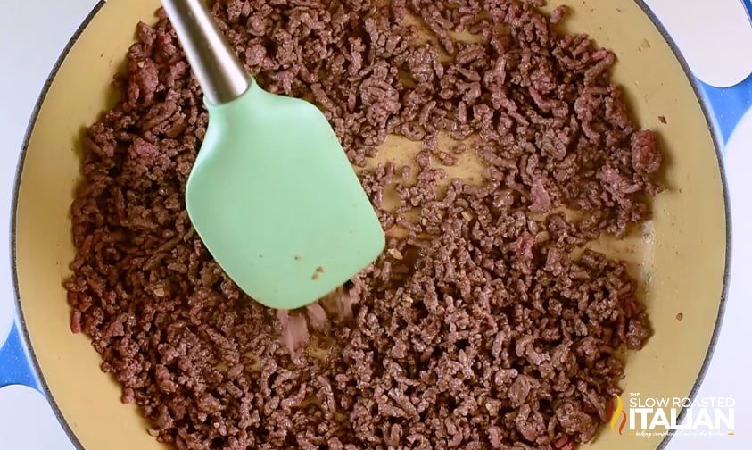 overhead: stirring browned hamburger in a skillet