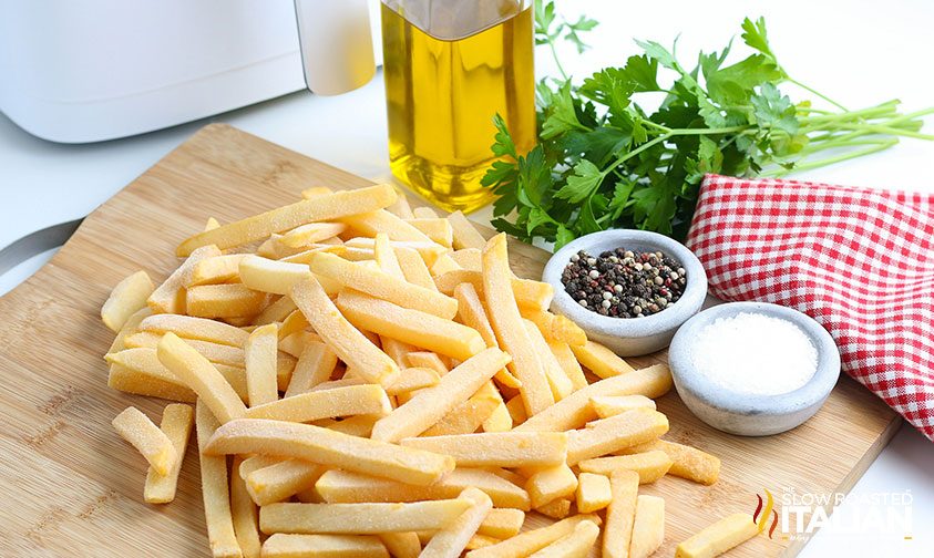 cutting board with frozen fries, oil, and salt and pepper