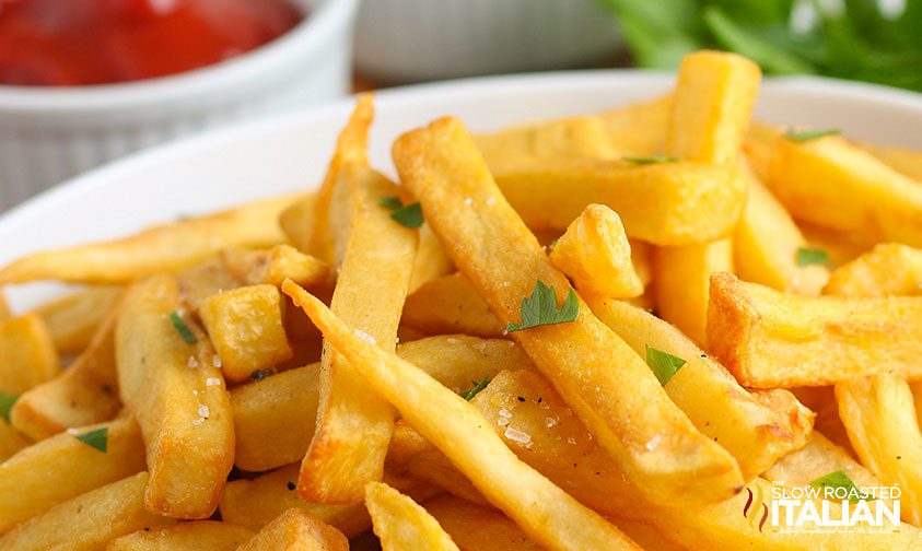 close up: plate of crispy fries with salt and parsley