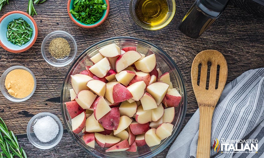 bowl of cubed red potatoes surrounded by oil and seasonings