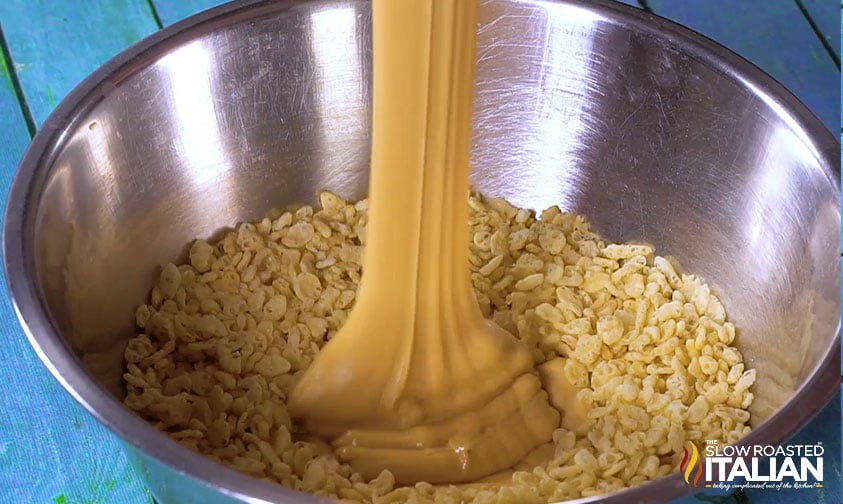 pouring melted peanut butter mixture over rice cereal