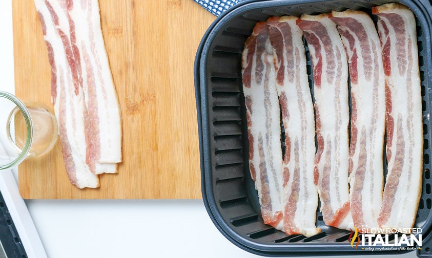 strips of uncooked bacon in air fryer basket
