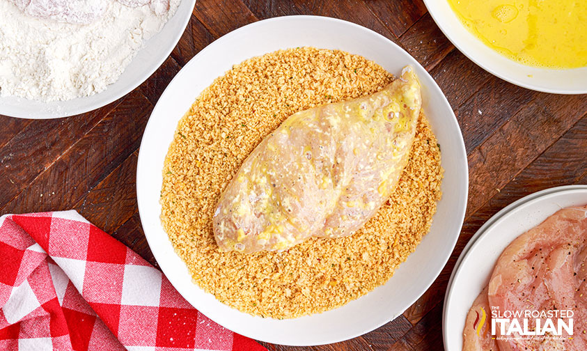 chicken cutlet in bowl of breadcrumbs