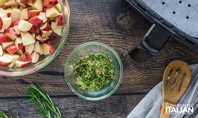 bowl of spices and herbs next to bowl of chopped red potatoes