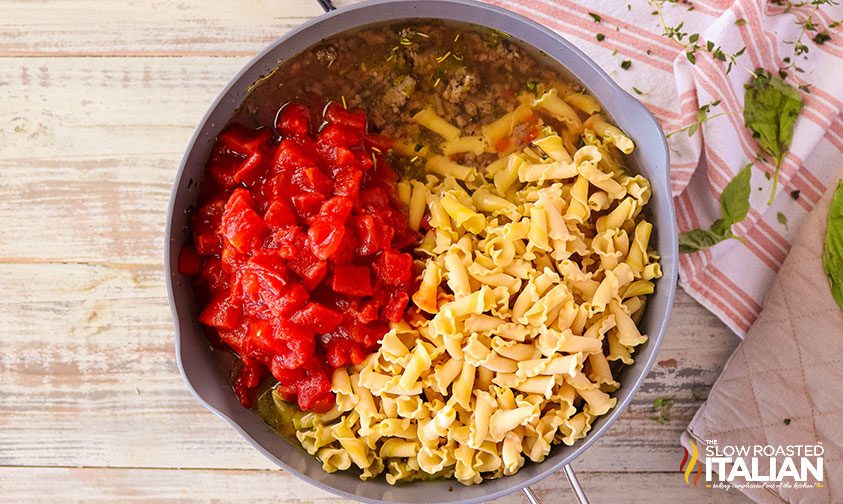 pasta and tomatoes in skillet with beef and broth