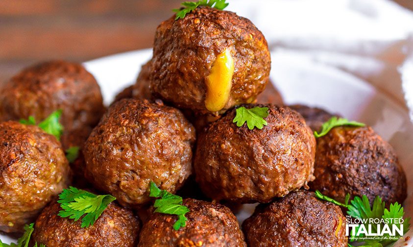 cheese oozing out of meatball on top of a stack