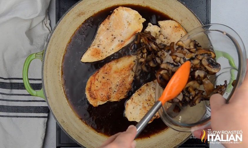adding mushrooms to chicken and sauce in dutch oven