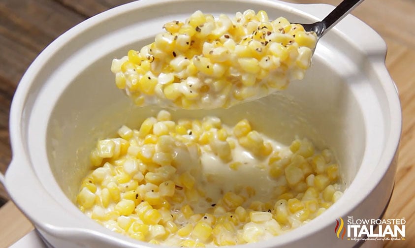 lifting spoonful of cream corn out of slow cooker