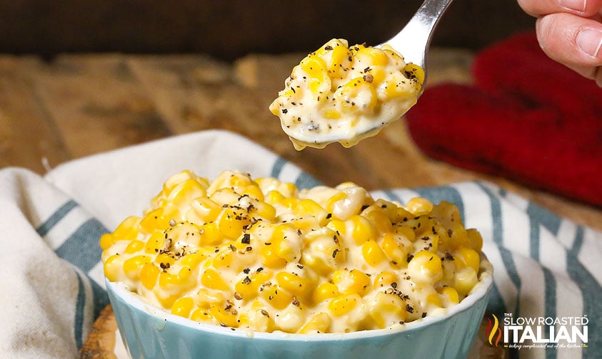lifting spoonful of creamed corn with pepper from dish