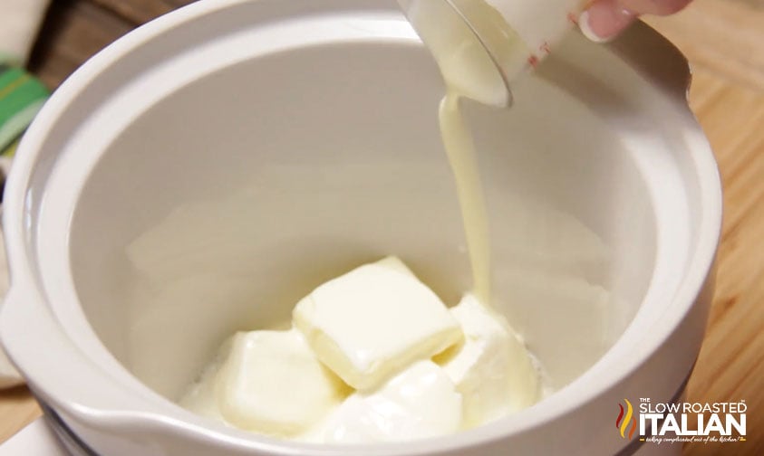 pouring cream into small crockpot with cream cheese