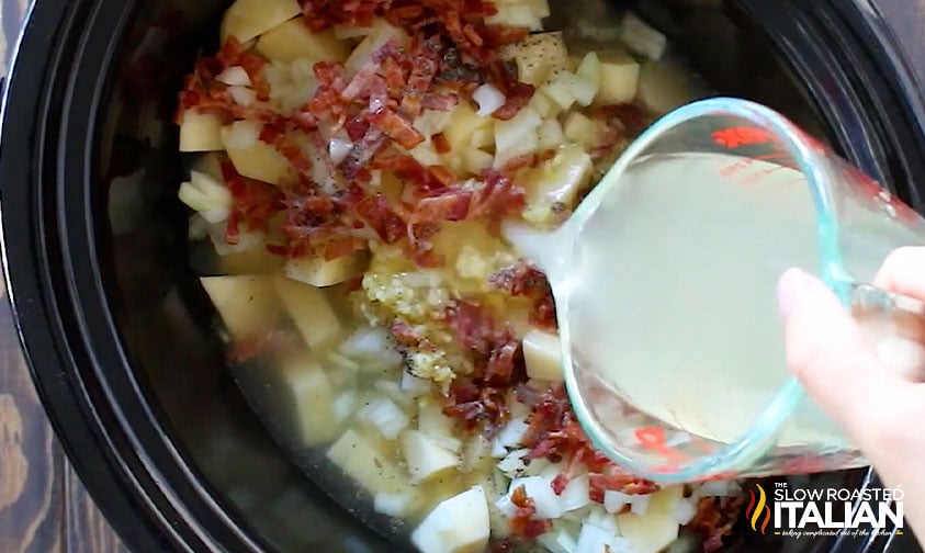 pouring chicken broth over soup ingredients in crock pot