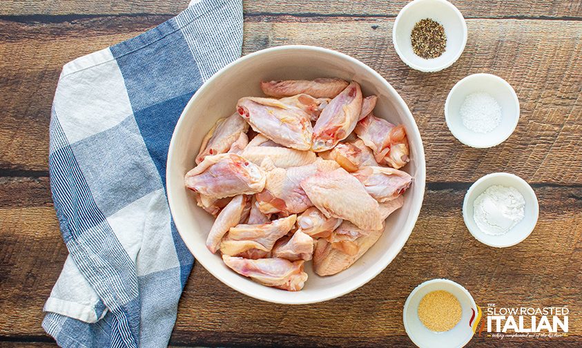raw chicken wings with bowls of seasonings