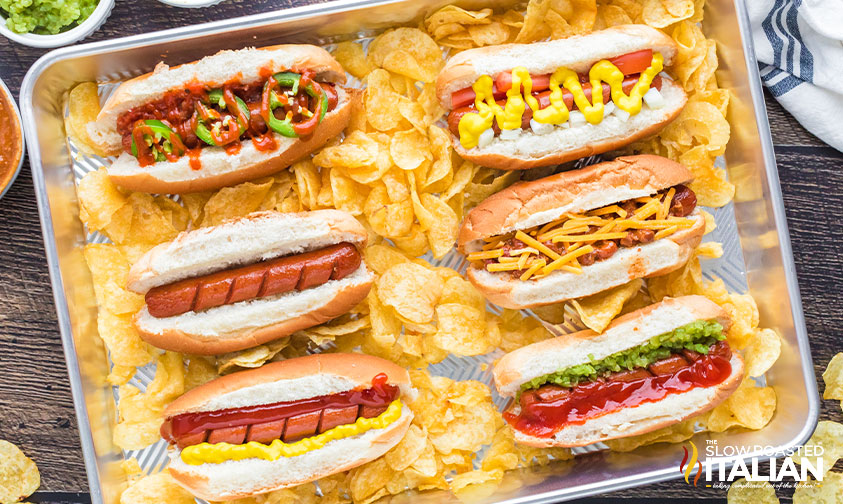 baking tray of hot dogs in buns with different toppings