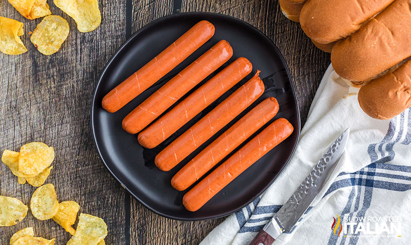 scored hot dogs on a black plate