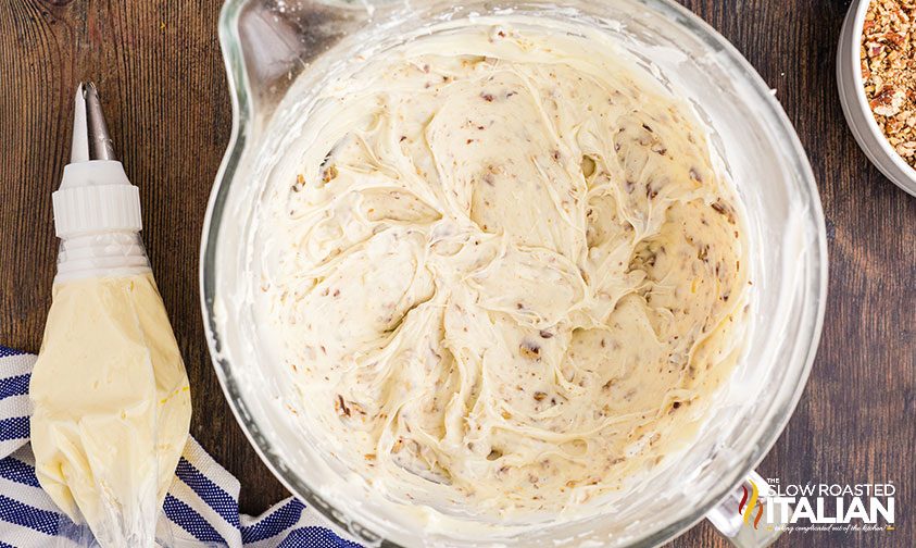 bowl of pecan cream cheese frosting in bowl and piping bag