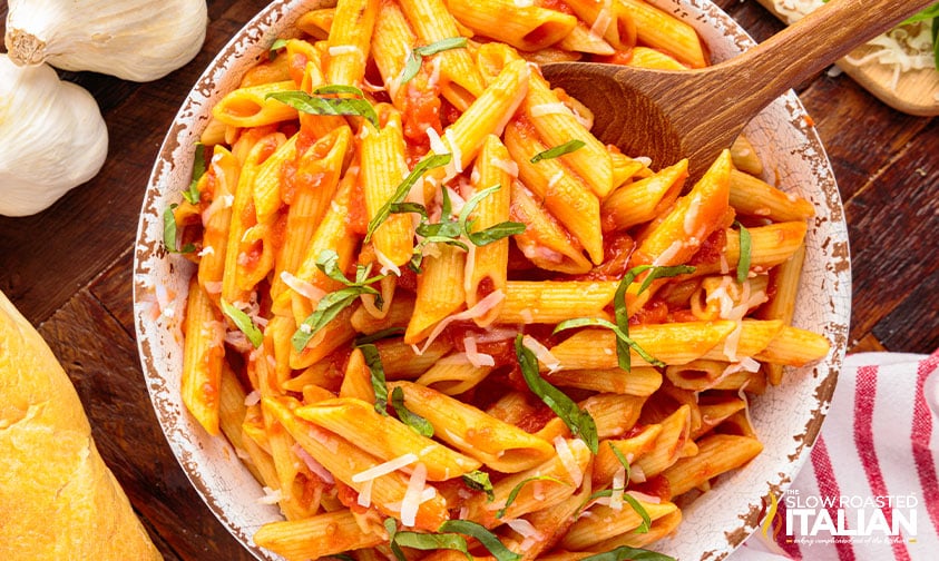 overhead: bowl of penne with pomodoro sauce, basil, and parmesan