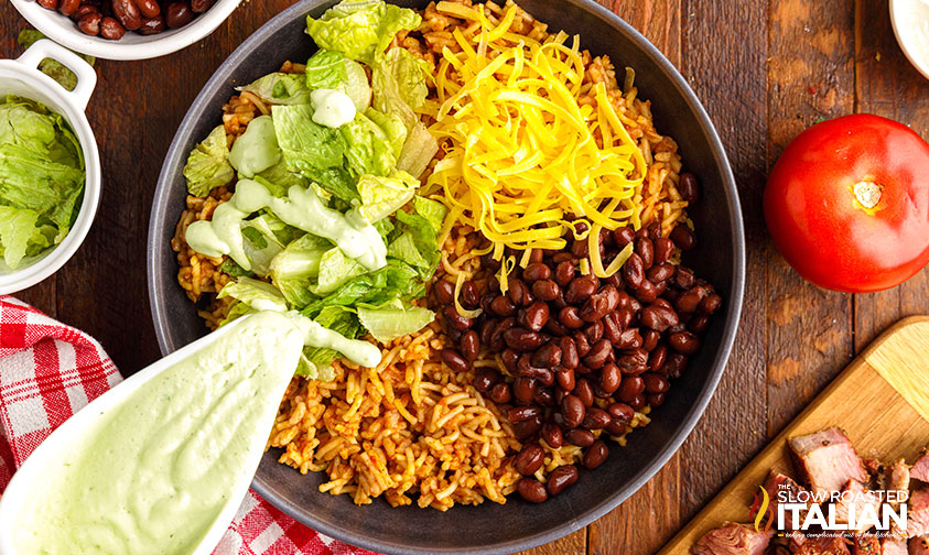 pouring creamy dressing over power bowl ingredients