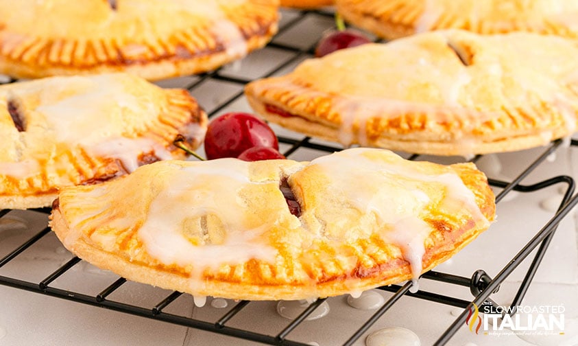 cherry hand pies on cooling rack drizzled with icing