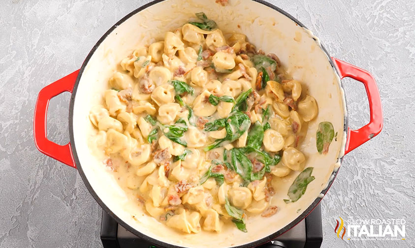 adding spinach to tortellini in a pot