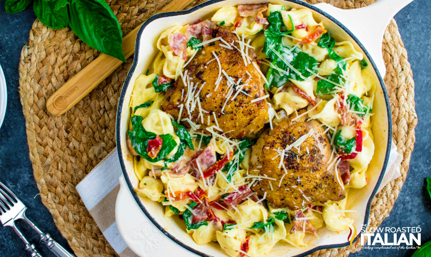 overhead: skillet with tortellini, spinach, sun dried tomatoes, and chicken thighs