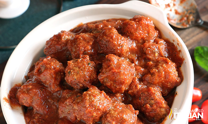 crockpot of meatballs and marinara next to basil and tomatoes