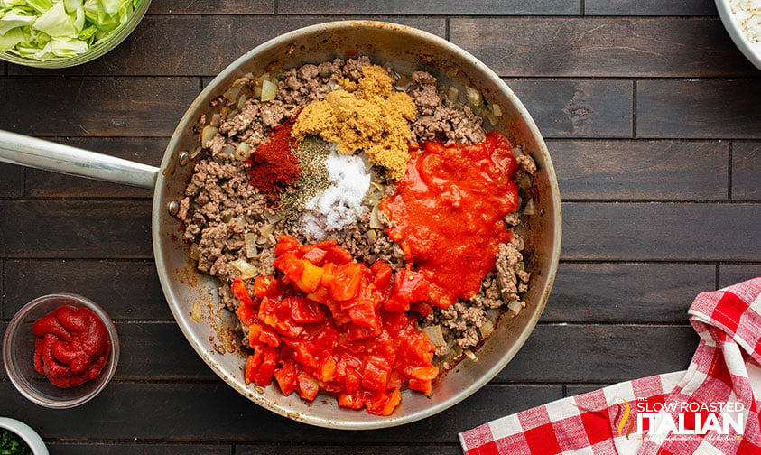 adding crushed tomatoes and spices to ground beef