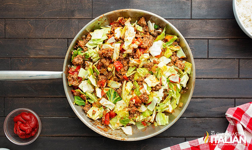 adding cabbage to the skillet