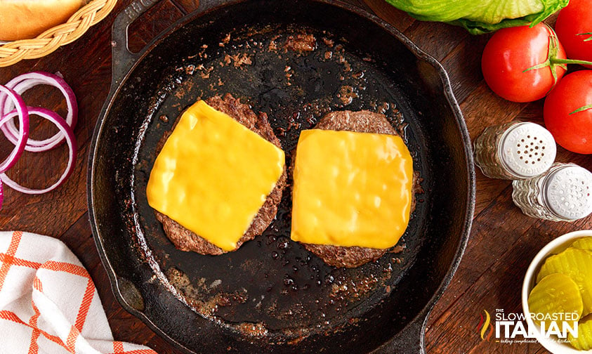 two beef patties topped with cheese in skillet