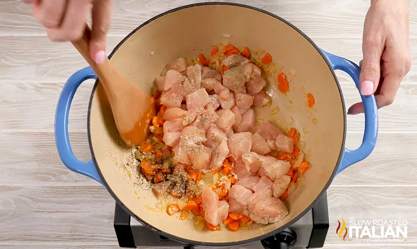 stirring chicken and spices into cooked veggies