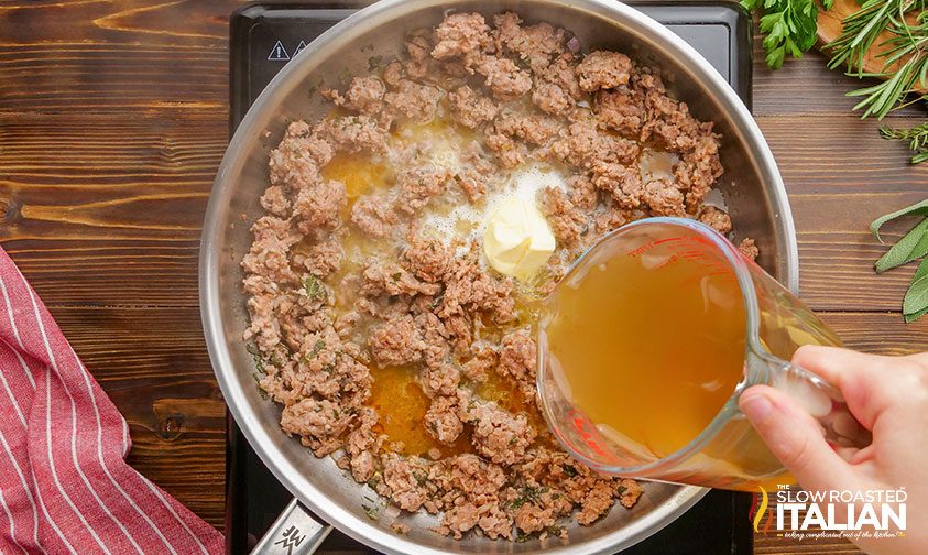 pouring stock into pan with sausage and butter