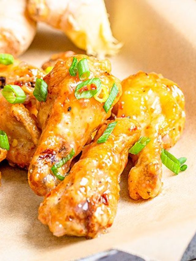 sweet chili wings topped with green onions on parchment lined baking sheet