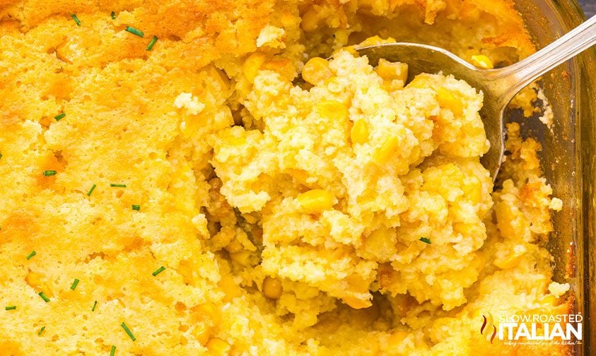 scooping a spoonful of corn casserole from pan