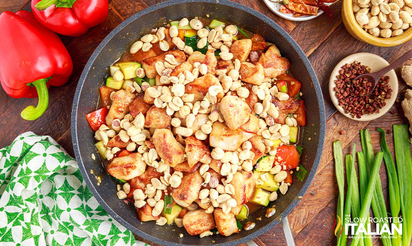 chicken, peanuts, veggies, and peppers in skillet