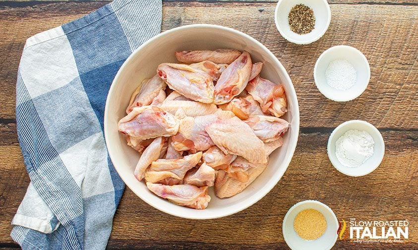 bowl of raw chicken wings next to bowls of baking powder and seasonings