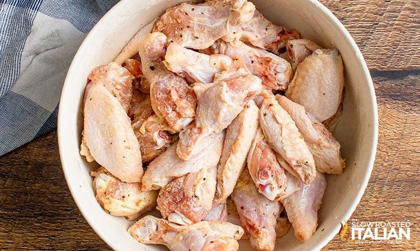 bowl of uncooked chicken wings coated in seasonings