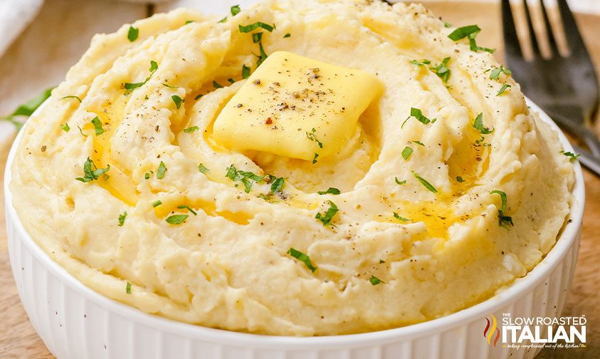 ramekin of mashed potatoes topped with butter and fresh parsley