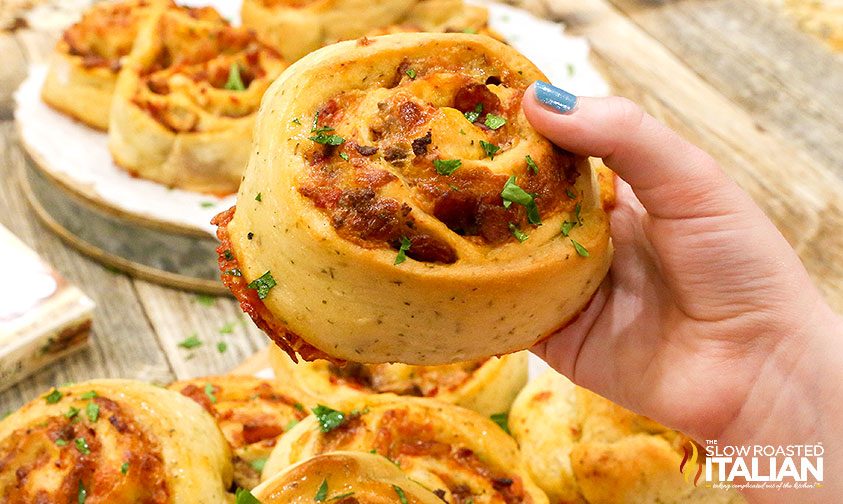 holding pizza pinwheel stuffed with meat and cheese