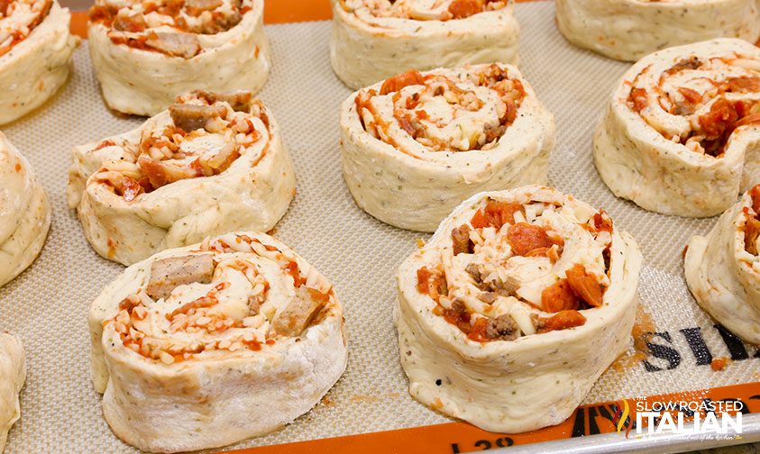 unbaked pizza pinwheels on silpat lined baking sheet