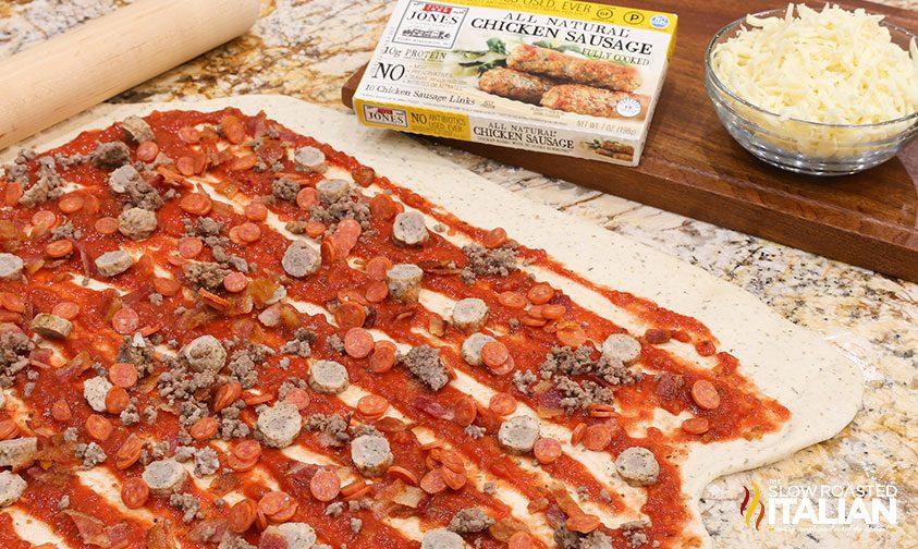 red sauce and meat toppings spread over pizza dough