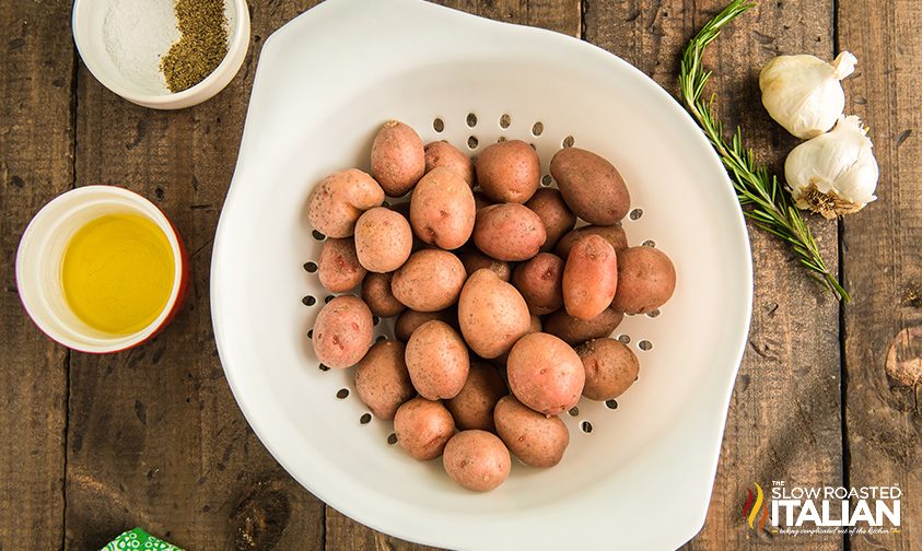 baby red potatoes in strainer surrounded by oil and seasonings