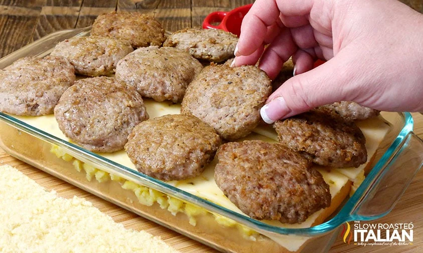 placing mini sausage patties on cheese and eggs in baking dish