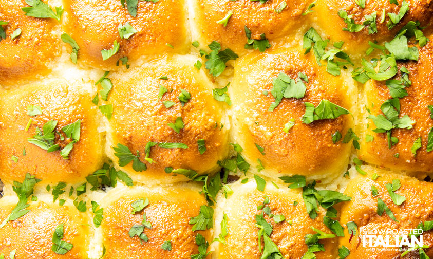 close up: buttery rolls topped with butter, cheese, and parsley