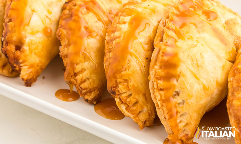 tray of apple hand pies drizzled with caramel sauce