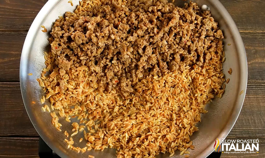 adding browned ground beef to rice in skillet