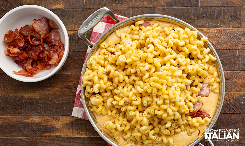 adding pasta and bacon to cheese sauce