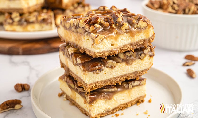 stack of three cut pecan cheesecake bars on a plate